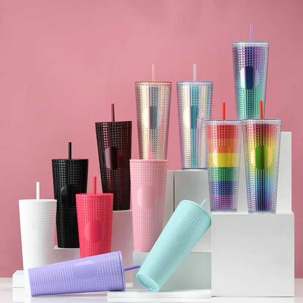 Assorted Matte Black Studded Bling Cup Tumblers in various colors displayed on pedestals with a pink background.