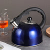Stainless Steel Whistling Flat Bottom Kettle in blue on a countertop with a glass of tea.