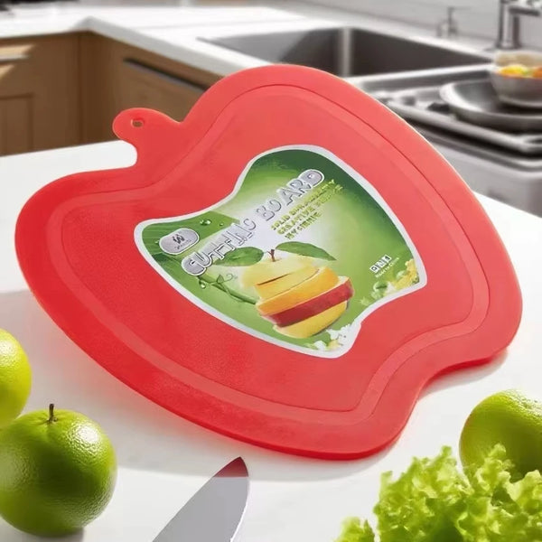 Apple Shape Plastic Cutting Board displayed in a kitchen setting with green apples and lettuce.