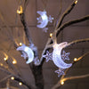 LED moon and star Ramadan string hanging light illuminating a decorated tree branch.