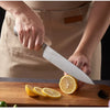 Person using a knife from a Stainless Steel 8 Piece Kitchen Knife Set to slice a lemon on a wooden cutting board.