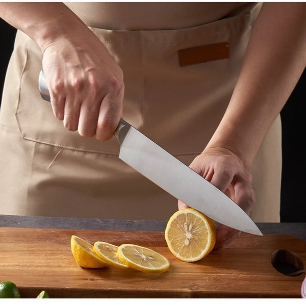 Person using a knife from a Stainless Steel 8 Piece Kitchen Knife Set to slice a lemon on a wooden cutting board.