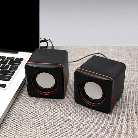 Mini USB Wired Speaker PC Speaker next to a laptop on a table, showcasing its compact design and modern style.