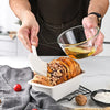 Person using Non-Stick Silicone Kitchen Utensils Set to brush oil on freshly baked bread.