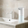 Automatic Soap Dispenser next to a modern sink in a clean bathroom setting.