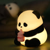 The Sitting Panda USB Night Light emitting a warm glow while holding a baby bottle, perfect for décor and mini planter.