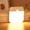 USB Rechargeable Motion Sensor LED Night Light on a table, providing soft light in a dark environment.