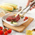 Using Heat Resistant Silicone Tipped Stainless Steel Tongs to handle meat on a cutting board with fresh vegetables.