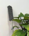 Telescopic Microfiber Removable Duster leaning next to green leafy plant against a white wall.