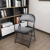 Black Padded Folding Chair with Steel Frame positioned in a modern interior with bookshelves.