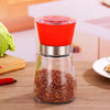 Manual Stainless Steel Pepper & Salt Grinder Mill with a red top and glass body, perfect for grinding spices.
