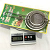Stainless Steel Mesh Strainer Filter Spoon displayed on a kitchen scale with a packaging background.