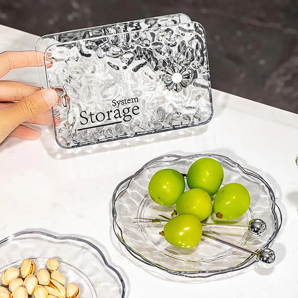 Hand holding System Storage container next to 6 Pc Flower-Shaped Snack Tray with green grapes and snacks.