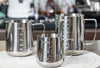 Silver Coffee Latte and Milk Frothing Pitcher 350ML displayed with other milk frothing pitchers on a kitchen counter.