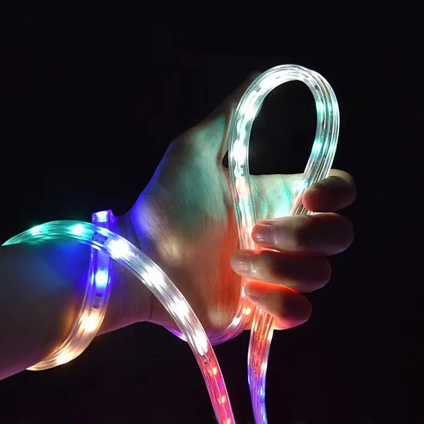 Hand holding a colorful 220V High Voltage Light Strip glowing in multiple colors against a dark background.