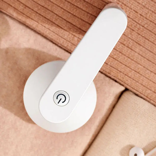 Portable USB Rechargeable Fabric Shaver and Lint Remover on a soft surface.