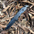4-Function Portable Stainless Steel Survival Knife on dry leaves, showcasing its sleek design and sharp blade.