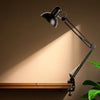 Flexible Adjustable Swing Arm Clip Desk Lamp providing focused task lighting on a wooden desk.