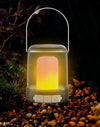 Portable USB Camping & Tent Lamp illuminated in nature amidst pebbles and plants on a rainy night.