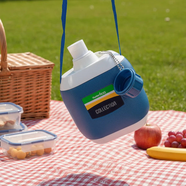 Large Capacity Leakproof Sports Water Bottle hanging in a picnic setting with food containers.