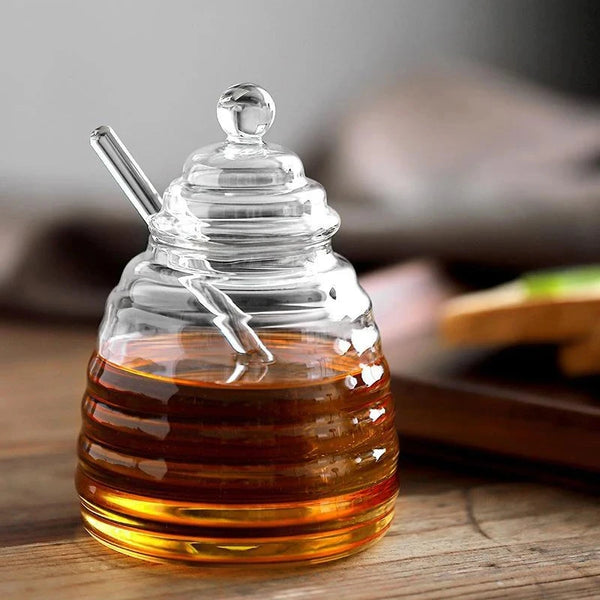 Hand-Blown Bee-Shaped Borosilicate Glass Honey Jar with honey and dipper on wooden table