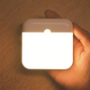 USB Rechargeable Motion Sensor LED Night Light held in hand, illuminating a warm glow.