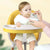 Baby eating from a spoon in a Portable Baby Booster Seat Harness during mealtime.