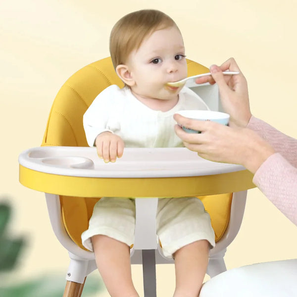 Baby eating from a spoon in a Portable Baby Booster Seat Harness during mealtime.