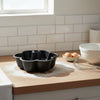 25cm Carbon Steel Flower Pattern Non-stick Cake Pan on wooden countertop with kitchen utensils and eggs.