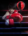 A child practicing with the Height Adjustable Freestanding Reflex Bag Kit while wearing boxing gloves.