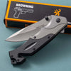 G10 Stainless Steel Folding Hunting Knife displayed on a teal surface with Browning packaging in the background.