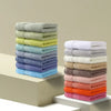 Stack of colorful Thick Cotton Face and Hand Towels in various shades, showcasing softness and absorbency.