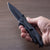 Hand holding the Iron Grip Full Metal Survival Folding Knife with a sleek black blade and textured grip.