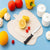 Apple Shape Plastic Cutting Board with fresh vegetables and knife on a blue counter.