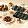 Delicious cannelés baked in a Carbon Steel 6-Cup Cannelé Baking Tray, showcased with pastries and desserts.