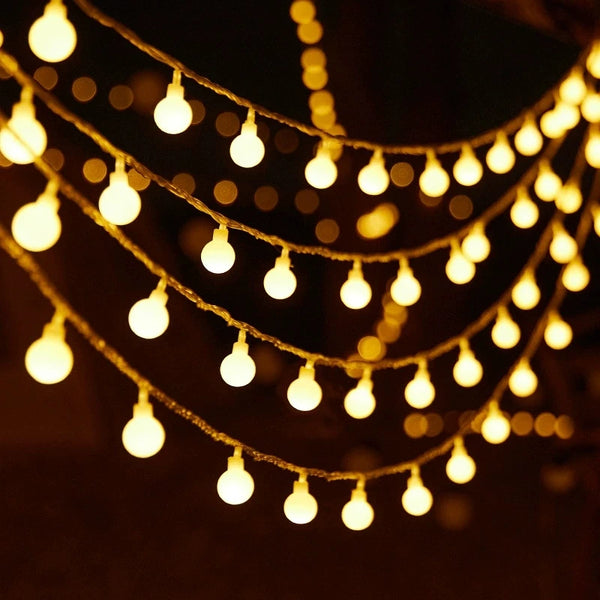 Bubble Ball Fairy String Lights glowing softly across a dark background with warm yellow light accents.