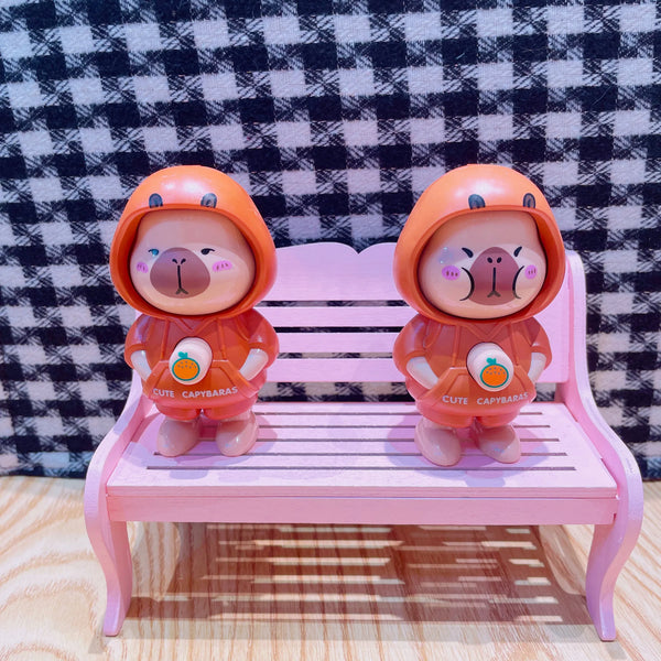 Super Cute Rotatable Head Capybara Keychain figures on a pink bench, showcasing adorable designs and charm.