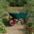 Heavy-Duty Garden Wheelbarrow with Pneumatic Wheel on a garden path surrounded by flowers and potted plants.