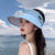 Women Rechargeable Cooling Fan Sun Visor worn by woman by the water on a sunny day.