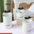 Plastic Round Storage Jar with Lid set of three white jars with decorative black lids on a light surface.