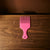Wide-Tooth Hair Pick Comb in pink color on a wooden surface with a shadow.