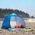 Automatic Pop-Up Beach Tent set up on a rocky beach, surrounded by colorful beach accessories and towels.