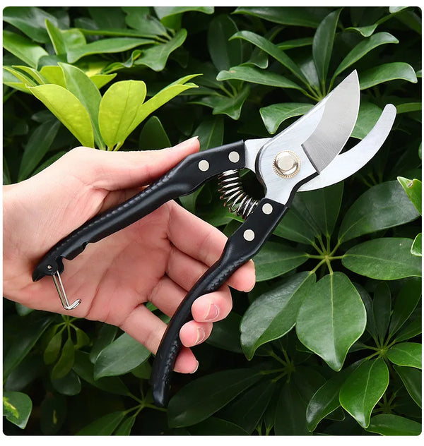 Steel Garden Bypass Pruner held in hand among vibrant green leaves for precise gardening cuts.