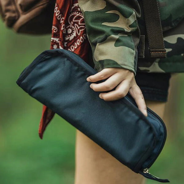 Person holding a compact Collapsible Portable Camping Stool in a black carrying case outdoors.
