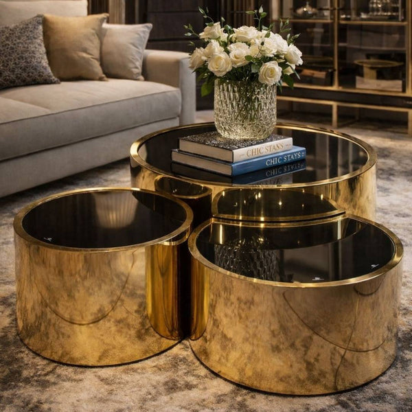 Lucid Gold 3-Piece Nesting Coffee Table Set with sleek gold finish and black glass tops, styled with flowers and books.