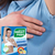 Woman showing Disposable Underarm Sweat Pads packaging while applying it underarm to prevent sweat marks.