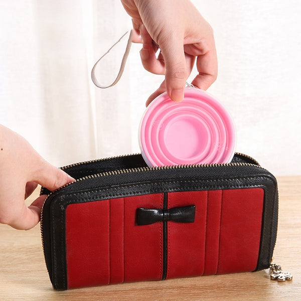 Portable Collapsible Silicone Travel Cup being taken out of a stylish red wallet for convenience.