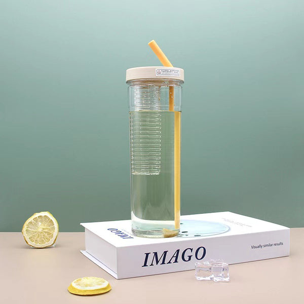 Reusable Clear Sports Water Bottle with Straw placed on a book with slices of lemon and ice cubes.