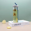Reusable Clear Sports Water Bottle with Straw filled with iced tea and lemon slices on a book.
