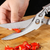 User using a chicken shredder tool to effectively chop red chili peppers on a wooden cutting board.